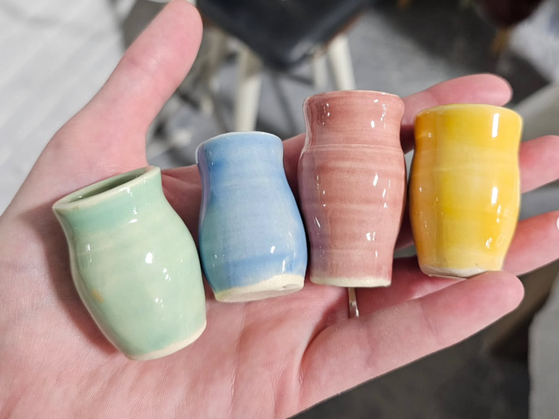 A hand holding four mini pots